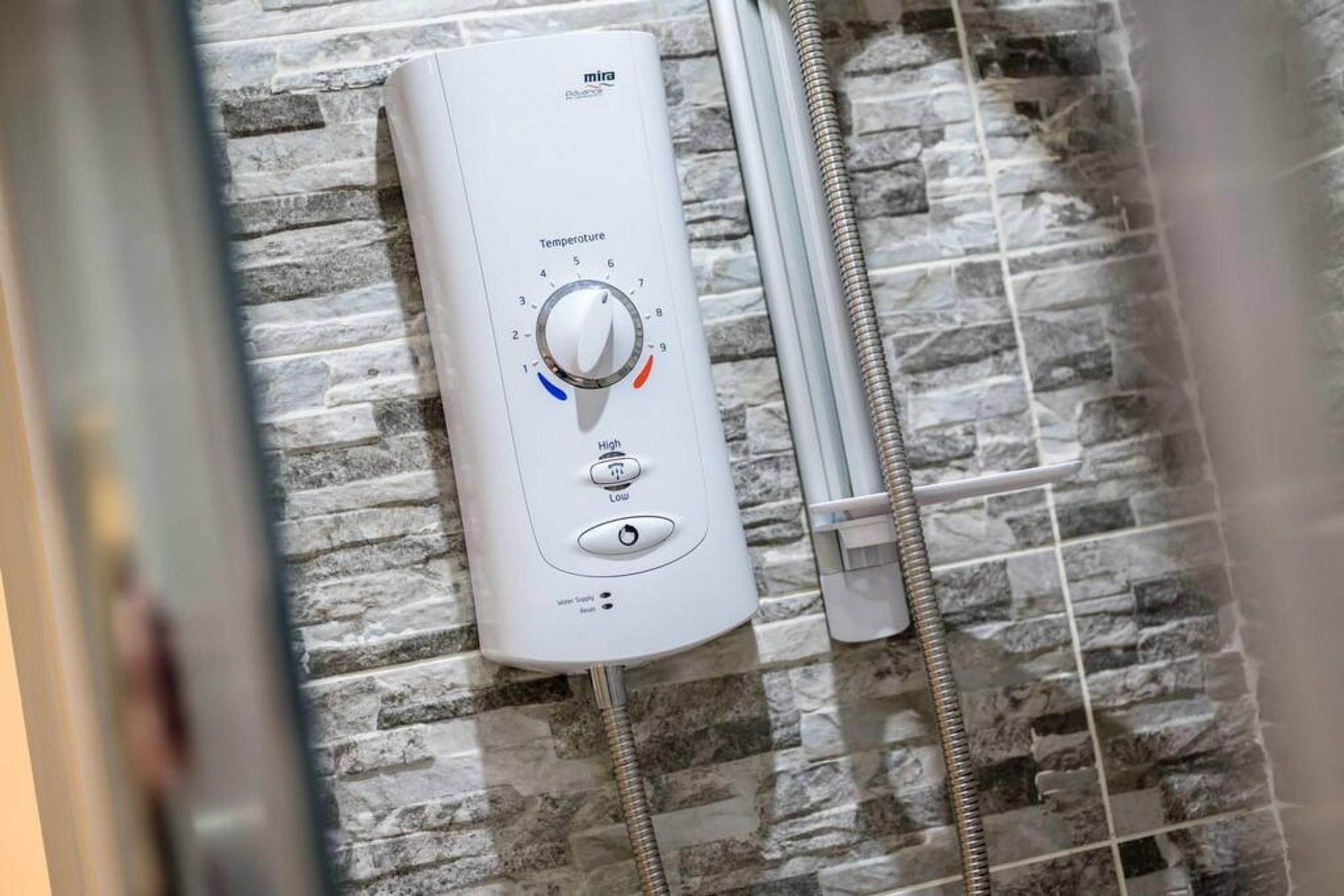 Een warmwaterboiler met een draaiknop voor de temperatuur, een aan/uit-knop en een waterdebietregelaar.