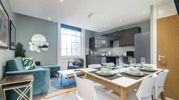 A modern living space with a dining area, kitchen, and seating area.