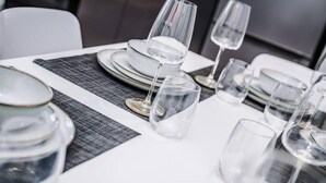 A dining table set with clear glassware and plates, arranged on a textured table runner.