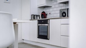 Een moderne keuken met witte kasten, een ingebouwde oven en een koffieapparaat.
