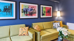 A room with a green sofa, two framed pictures on the wall, and a vase with flowers on a wooden table. - Host Apartments The Falkner Quarters III (Liverpool)