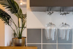 Un interior modern amb una planta en test, un camió de rajoles i dues copes de vi penjades.