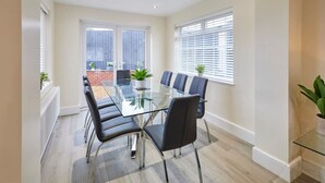 A modern meeting room with a glass table, black chairs, and potted plants. - Host Stay Violet s View (Whitby)