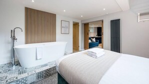 A modern hotel room with a large bed, a freestanding bathtub, and a separate shower area. - Host Apartments The Georgian Coach House 2 (Liverpool)