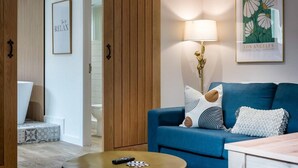A modern living room with a blue sofa, a lamp, and a framed picture of flowers. - Host Apartments The Georgian Coach House 2 (Liverpool)