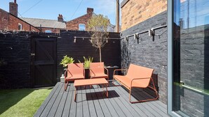 A deck with outdoor furniture, a small tree, and a black wall. - Host Stay Bath Street (Saltburn-by-the-Sea)