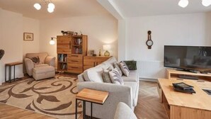 Ein modernes Wohnzimmer mit Sofa, Couchtisch, Fernseher und Holzmöbeln.