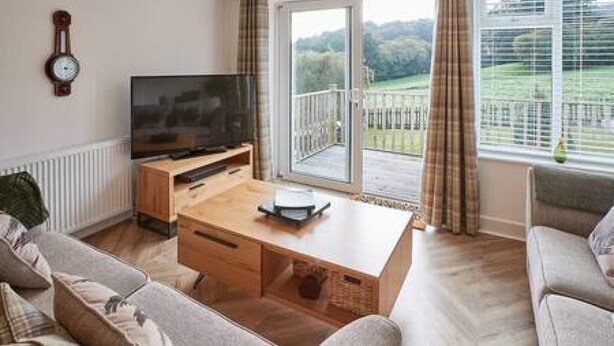 Ein Wohnzimmer mit Fernseher, Holztisch und zwei Sofas.