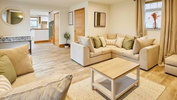 A modern living room with a sofa set, a coffee table, and a dining area in the background. - Host Stay Fawcett Cottage (York)