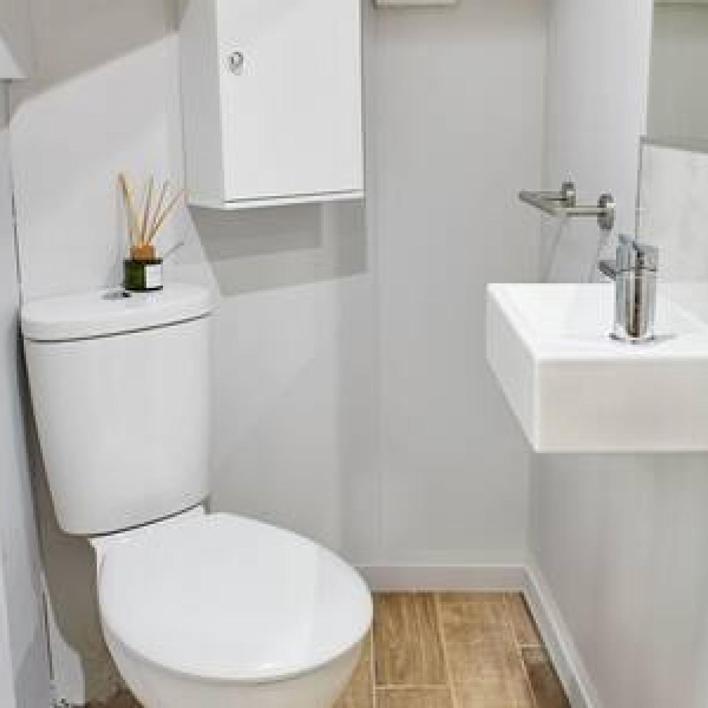 Une salle de bain moderne avec des toilettes blanches, un lavabo blanc et un miroir au-dessus du lavabo.