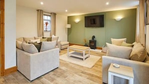 A living room with two sofas, a coffee table, and a TV mounted on the wall. - Host Stay Fawcett Cottage (York)