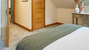A bedroom with a large bed, a wooden wardrobe, a small table with a vase, and a skylight. - Host Stay Fawcett Cottage (York)