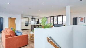 A modern living room with a sofa, a staircase, and a view of the kitchen and dining area. - Host Stay The Knight Street Penthouse I (Liverpool)