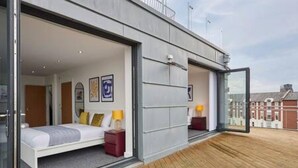 A modern bedroom with a large bed, a nightstand, and a glass door leading to a balcony. - Host Stay The Knight Street Penthouse I (Liverpool)