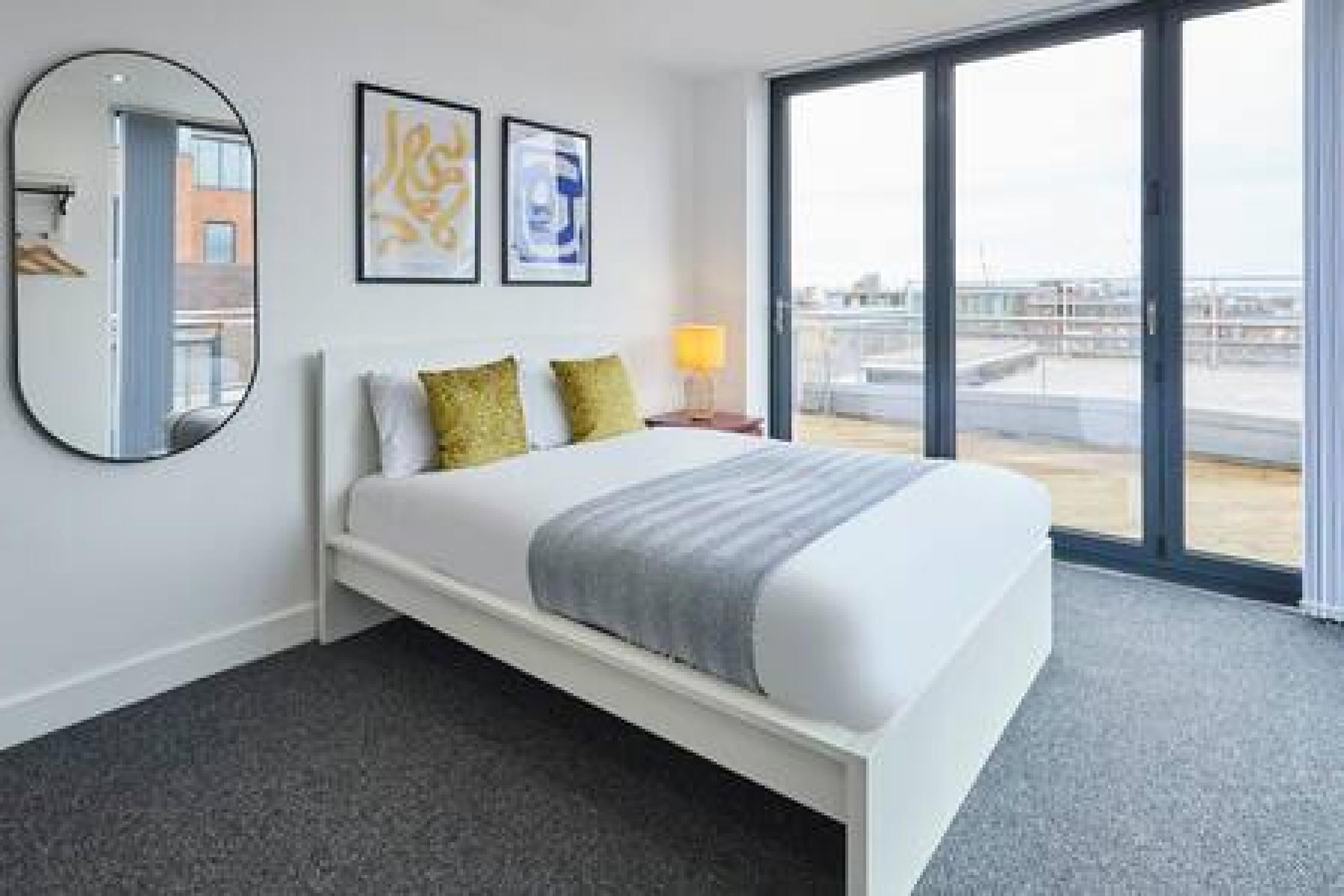 A hotel room with a bed, a large window, and a view of the cityscape.