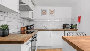 Uma cozinha moderna com armários brancos, bancada de madeira e micro-ondas.
