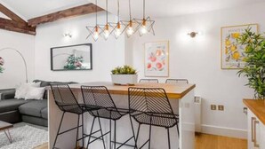 Uma cozinha moderna com ilha central, cadeiras de arame pretas e iluminação pendente.
