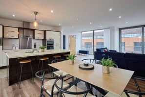 A modern kitchen with a central island, bar stools, and a dining table with chairs. - Host Stay The Knight Street Penthouse II (Liverpool)