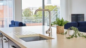A modern kitchen with a built-in sink, a stainless steel faucet, and a potted plant on the counter. - Host Stay The Knight Street Penthouse II (Liverpool)