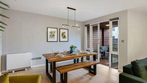 A dining area with a wooden table and benches, a green chair, and a pendant light. - Host Stay Ropewalks Quarters III (Liverpool)
