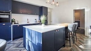 Una cocina moderna con gabinetes azul oscuro, una encimera blanca y una isla grande con taburetes de bar.