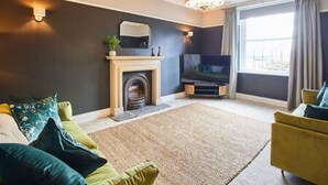 Una sala de estar moderna con chimenea, televisor de pantalla plana y un ventanal con cortinas.