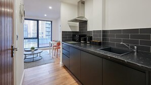 Une cuisine moderne avec des plans de travail sombres, un évier noir et une hotte aspirante.