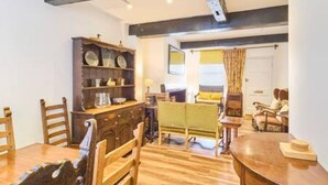 A cozy room with wooden furniture, a green sofa, and a dining table. - Host Stay St Radigunds House (Canterbury)