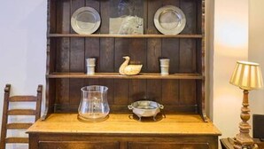 A wooden cabinet with shelves containing plates, a vase, and a swan-shaped object. - Host Stay St Radigunds House (Canterbury)