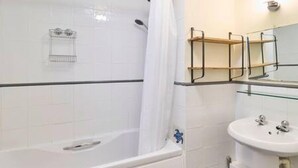 A bathroom with a bathtub, a sink, and a mirror. - Host Stay Cobb Court (Margate)
