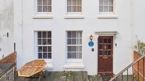 A white building with multiple windows, a wooden door, and a small outdoor seating area. - Host Stay Cobb Court (Margate)