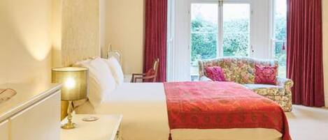 A bedroom with a bed, a nightstand, a lamp, and a window with curtains.