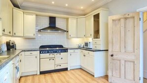 A kitchen with white cabinets, a stove, and a microwave. - Host Stay Bellevue Road (Ramsgate)