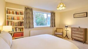 A bedroom with a large bed, a bookshelf, a dresser, and a window with curtains. - Host Stay Mayfield (Canterbury)