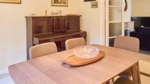 A dining area with a wooden table, chairs, and a piano. - Host Stay Mayfield (Canterbury)