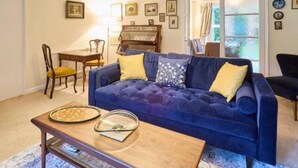 A living room with a blue sofa, a wooden coffee table, and a piano in the background. - Host Stay Mayfield (Canterbury)