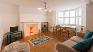 Ein geräumiges Wohnzimmer mit Kamin, Essbereich und Fernseher.