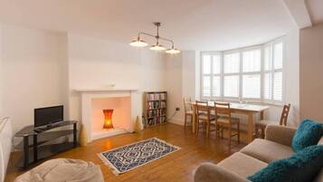 A spacious living room with a fireplace, a dining area, and a television.