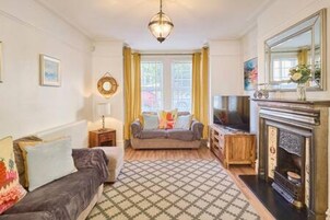 A living room with a fireplace, a sofa, a patterned rug, and a large mirror.