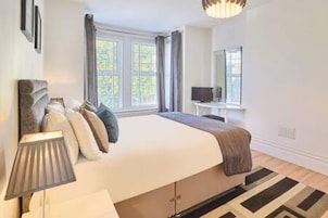 Una camera da letto con un letto, una televisione, una lampada e una finestra con tende.