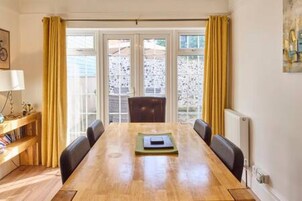 Un comedor con una mesa de madera, sillas y una estantería.
