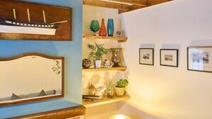 Una habitación con techo de madera, un modelo de barco en la pared y estanterías con objetos decorativos.