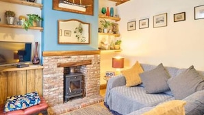 Una sala de estar acogedora con chimenea, un sofá con cojines y estanterías decoradas.