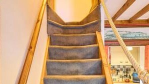 Una escalera con barandas de madera y escalones alfombrados que conducen a un piso superior.