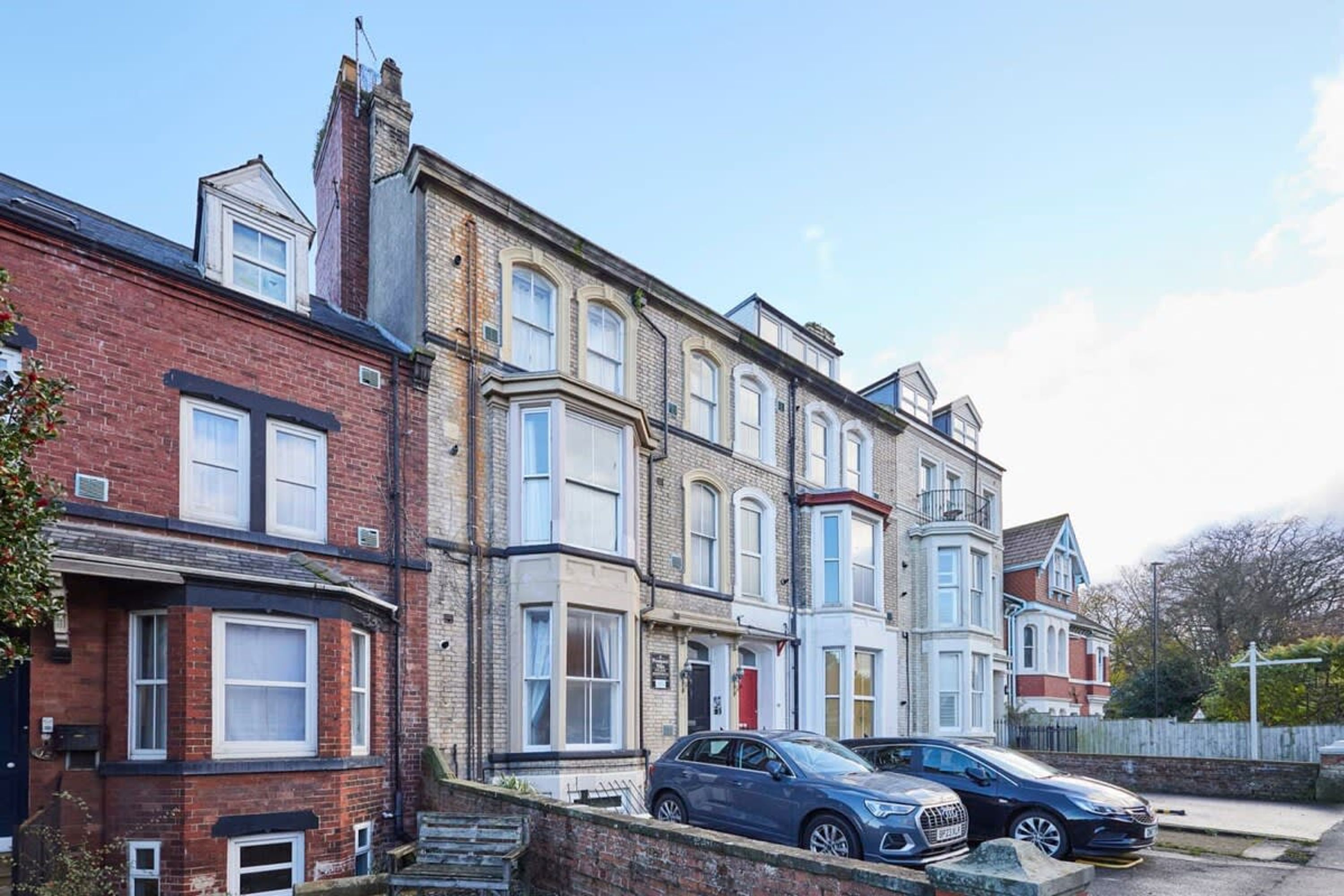 A row of terraced houses with a car parked in front.