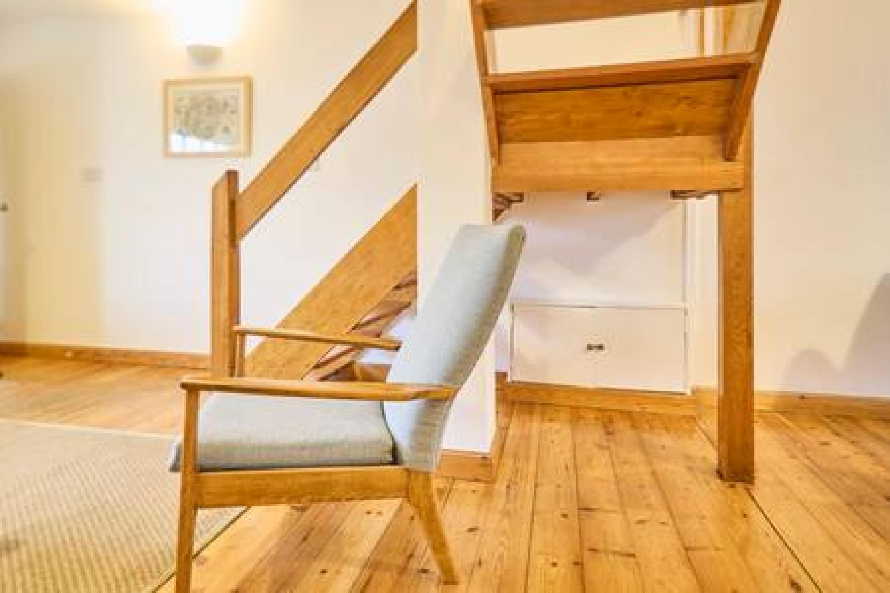 Ein Holzstuhl mit Kissen in einem Zimmer mit Holzboden und weißer Wand.