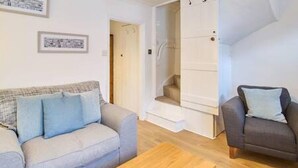 A modern living room with a grey sofa, a wooden coffee table, and a grey armchair. There is a staircase leading to another level. - Host Stay Prospect Place (Canterbury)