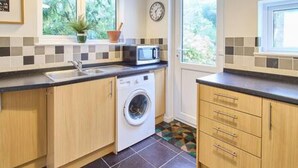 A compact kitchen with a washing machine, a microwave, and a sink. - Host Stay Prospect Place (Canterbury)