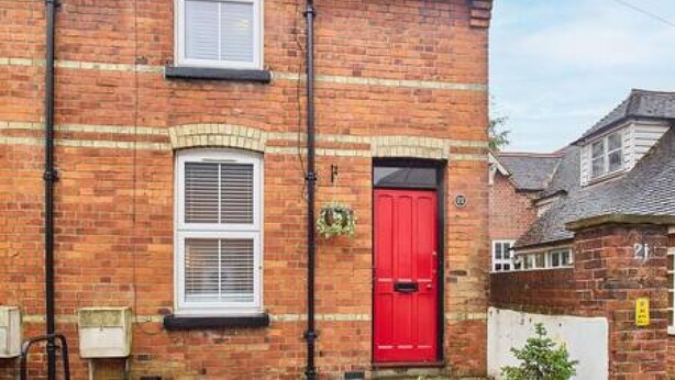 A red door on a brick building with a window above it and a small wreath hanging on the wall. - Host Stay Prospect Place (Canterbury)