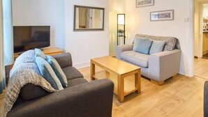 A living room with a sofa, a coffee table, and a flat-screen TV. - Host Stay Prospect Place (Canterbury)
